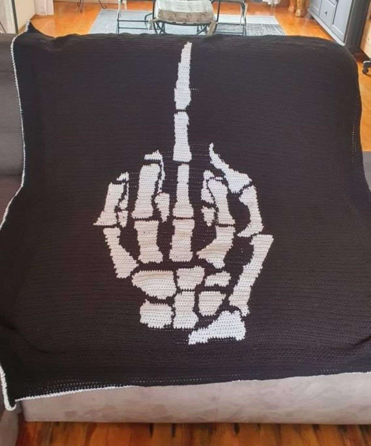 Customer-made skeleton middle finger crochet blanket in black and white yarn.